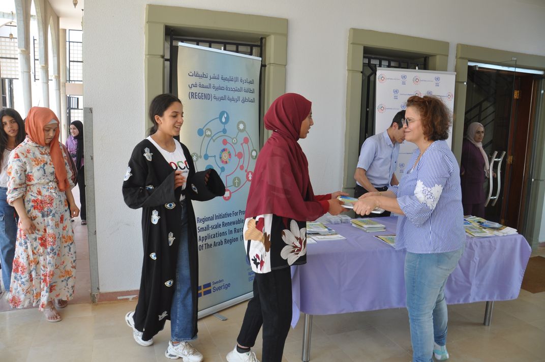 Woman giving a book to a teenager