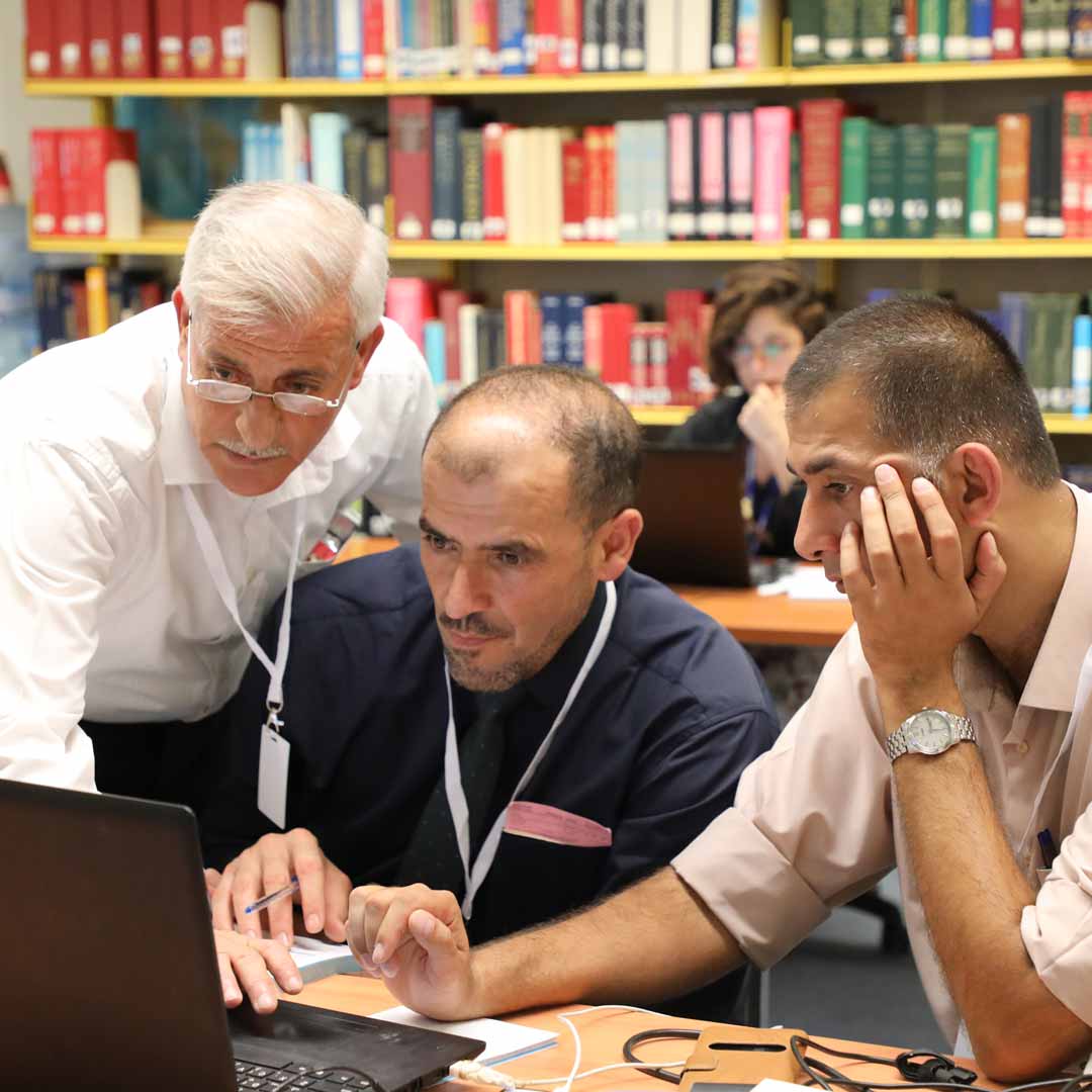 Three men sharing a laptop. Photo: MM/escwa