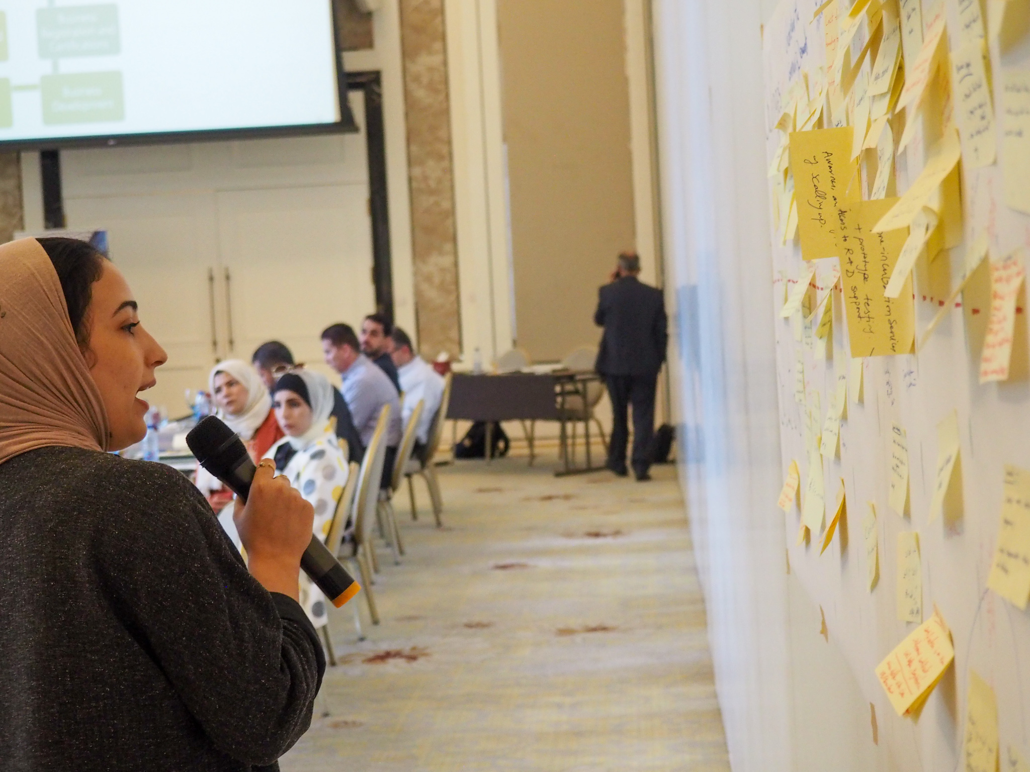 woman reading over microphone stickynotes placed on wall