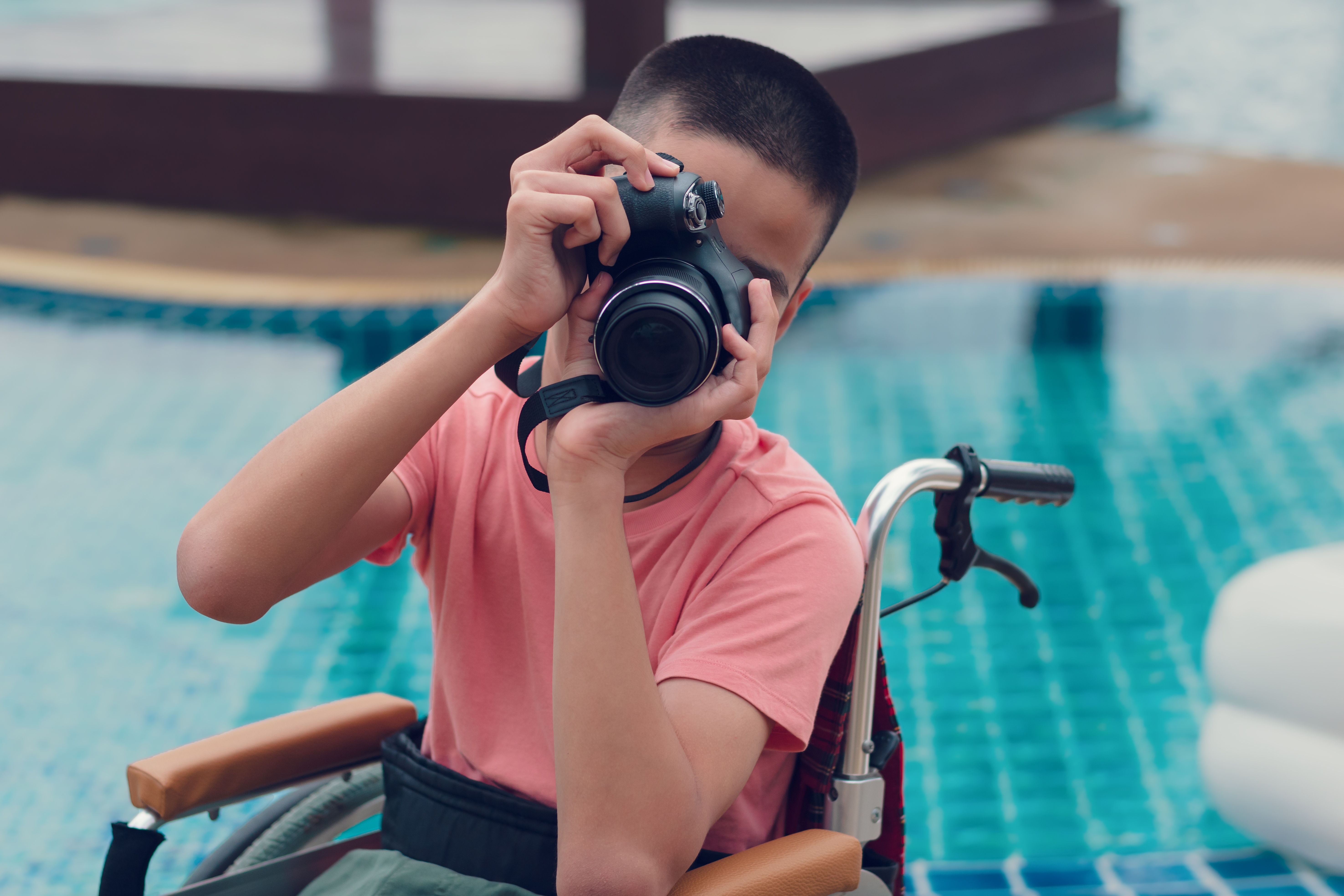 Photo of a child on a wheelcair holding a cam and taking photos