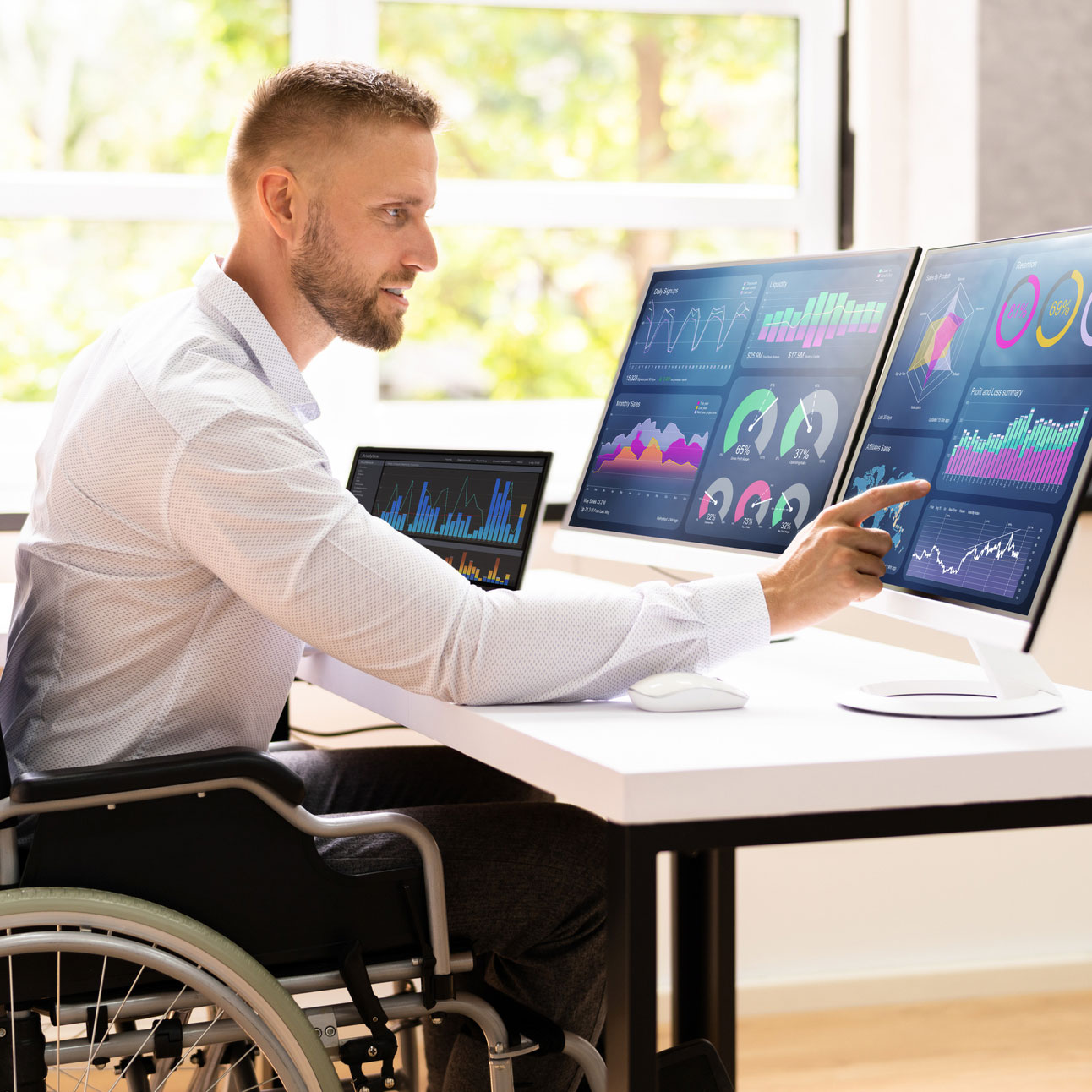 istock image: disabled man behind computer screens with statistics charts