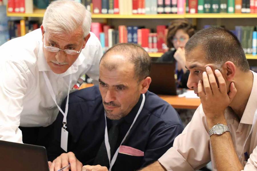 Three men sharing a laptop. Photo: MM/escwa