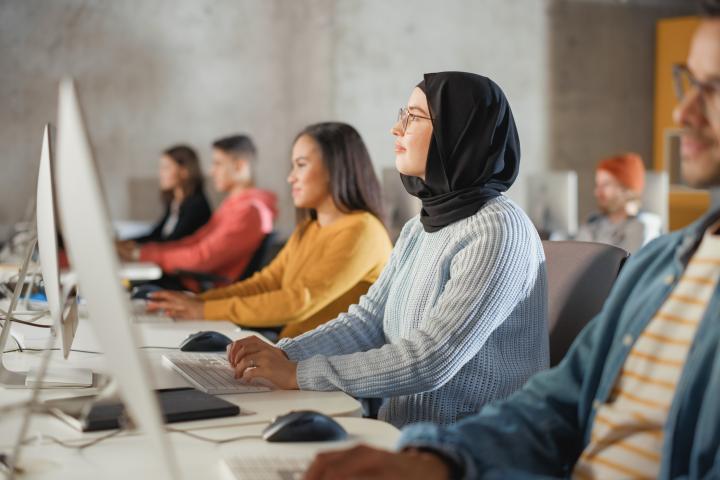 Smart Muslim Female Student in Hijab Studying in University with Diverse Multiethnic Classmates. Applying Her Knowledge to Acquire Academic Skills in Class