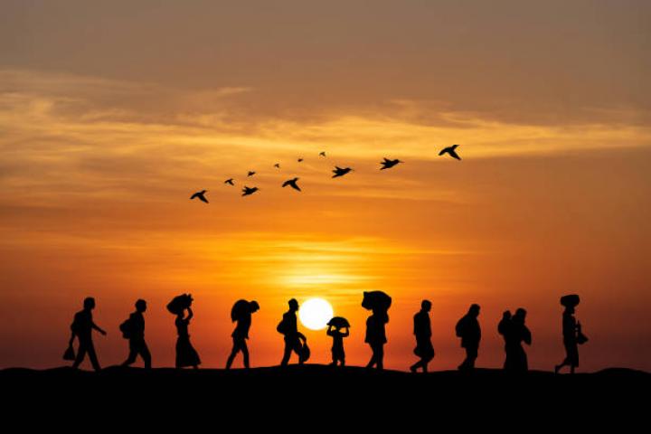 People walking across a field while the sun is setting